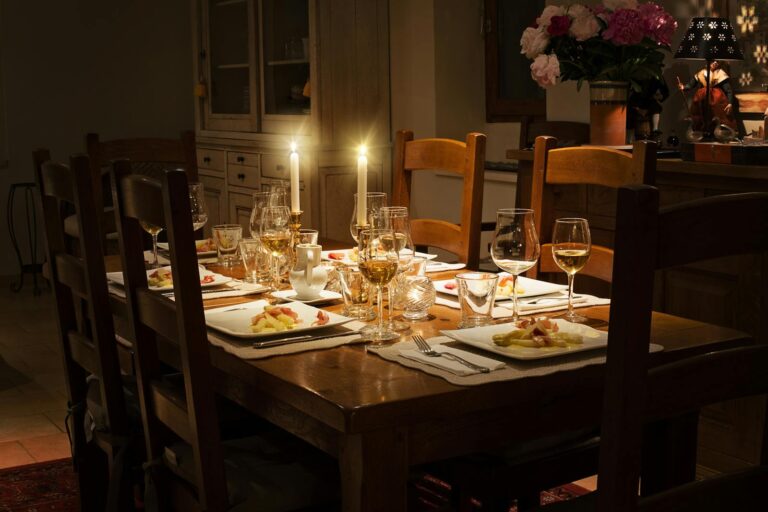 A cozy, candlelit table set for an elegant dinner, featuring fine tableware and a warm ambiance.